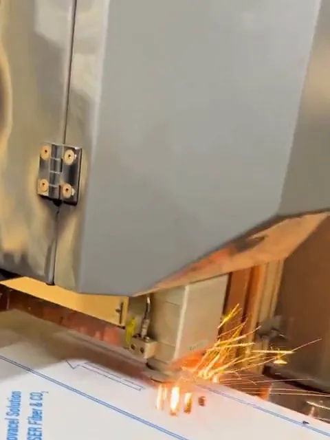 Cabeçote do laser cortando a chapa de inox, com faíscas, na fábrica em Joinville