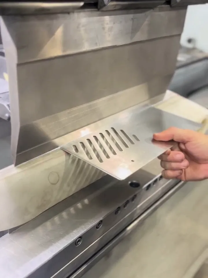 Peça de inox com as frestas já cortadas posicionada na dobradeira CNC